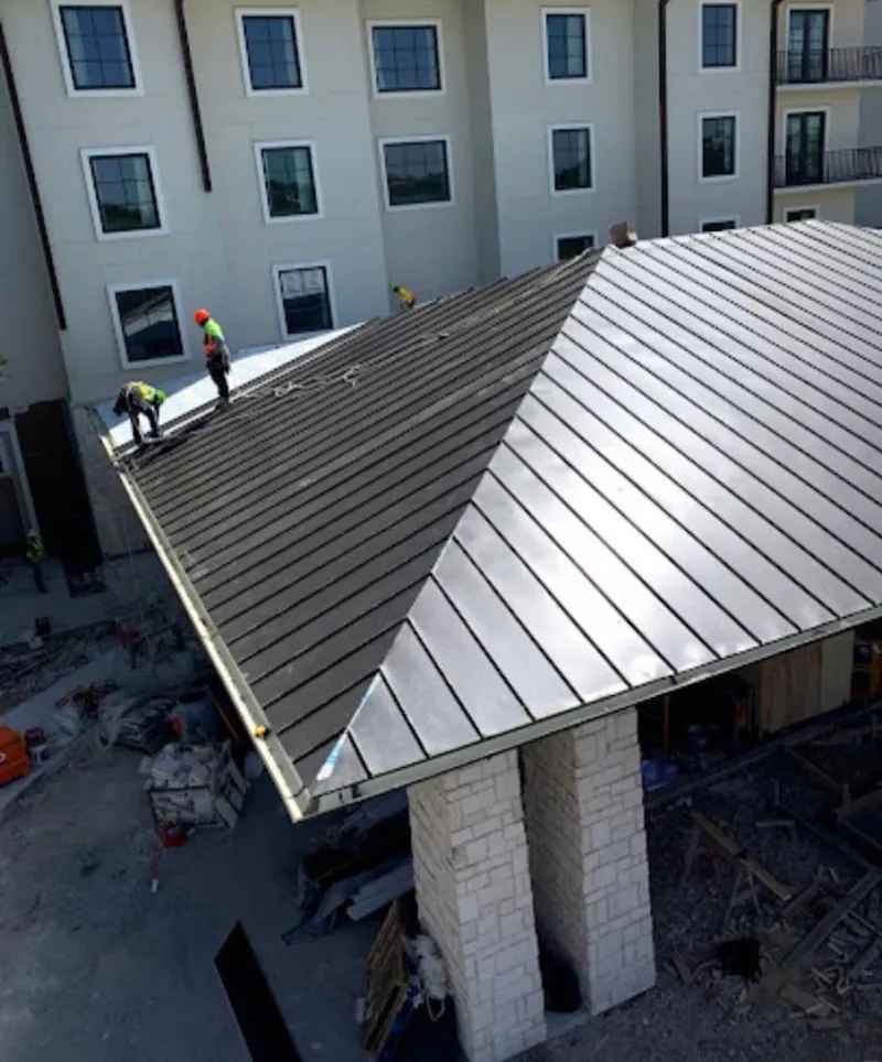 Crew installing standing seam metal roof panels on a commercial project in Stowe
